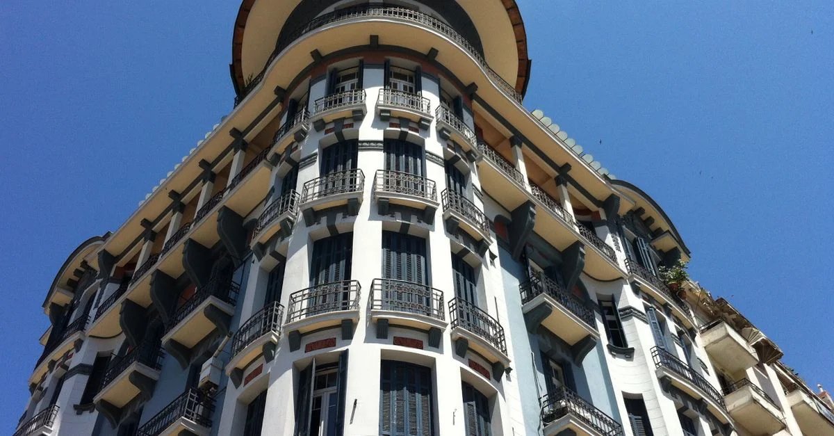 Un bâtiment Art Déco frappant avec un fer forgé intriqué sur fond d'un ciel bleu vibrant, mettant en valeur l'élégance architecturale.