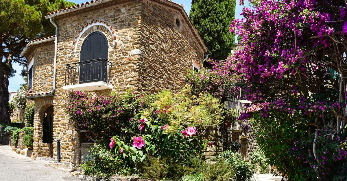 Belle maison en pierre entourée de fleurs vibrantes à Bormes-les-Mimosas, France.