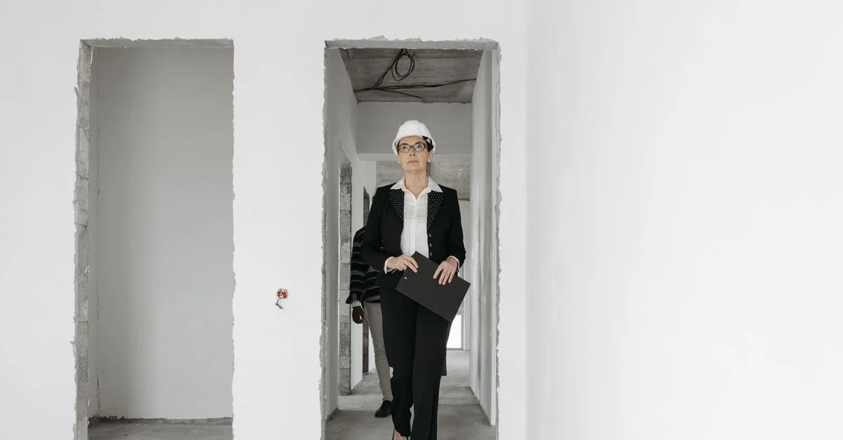 Femme d'affaires portant un casque de chantier, traversant un site de construction avec un dossier.