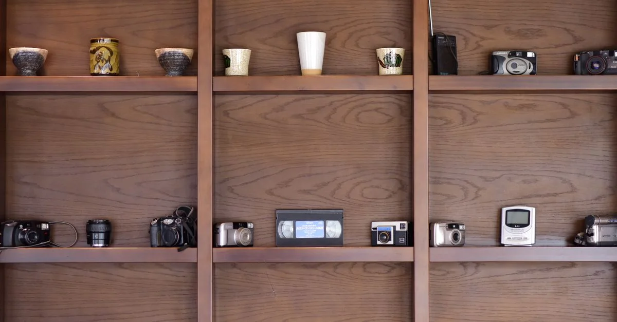Une collection d'appareils photo vintage et de mugs en céramique exposés sur des étagères en bois élégantes.