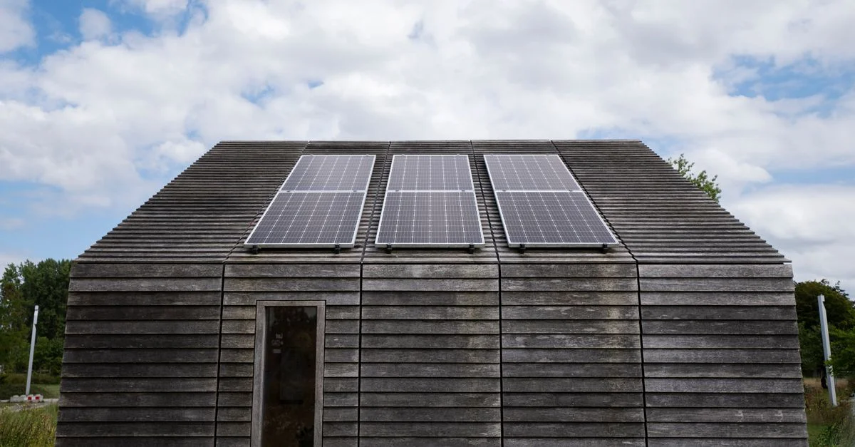 Maison en bois avec des panneaux solaires sous un ciel nuageux, promouvant l'énergie durable.