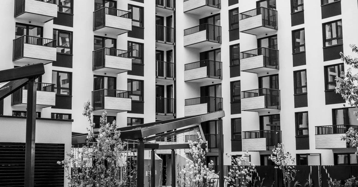 Immeuble d'appartements urbain contemporain avec balcons et cour, noir et blanc.