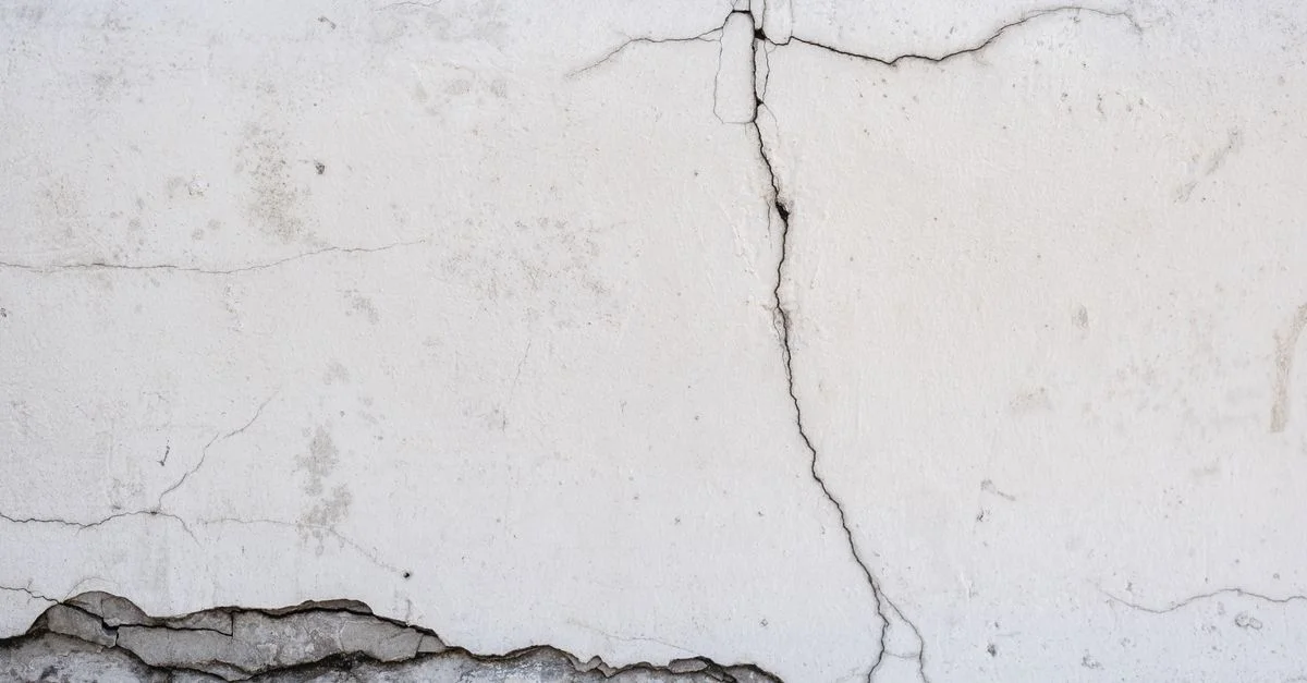 Gros plan d'un mur en béton fissuré montrant des détails de texture de surface.