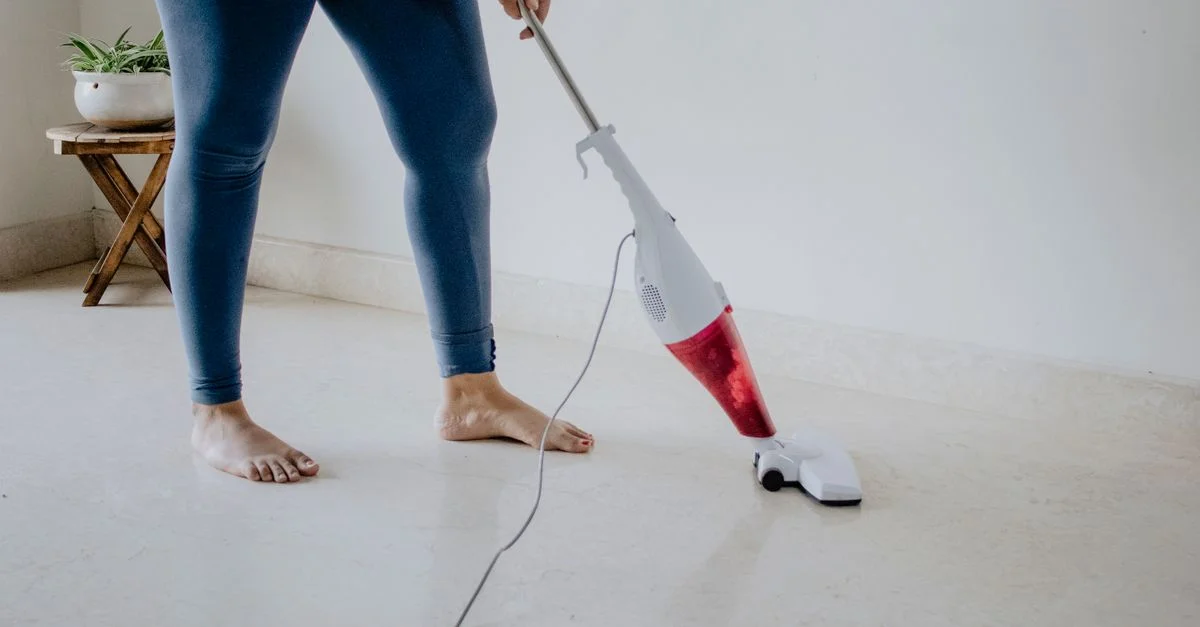 Gros plan d'une femme aspirant un sol en marbre propre pieds nus, mettant en avant le nettoyage et l'entretien de la maison.