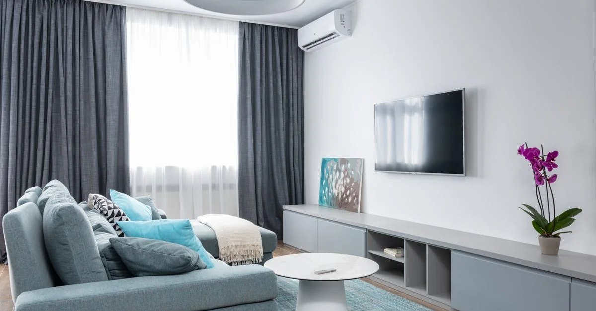 Salon moderne lumineux avec un canapé bleu confortable, décoration minimale et plante d'intérieur.