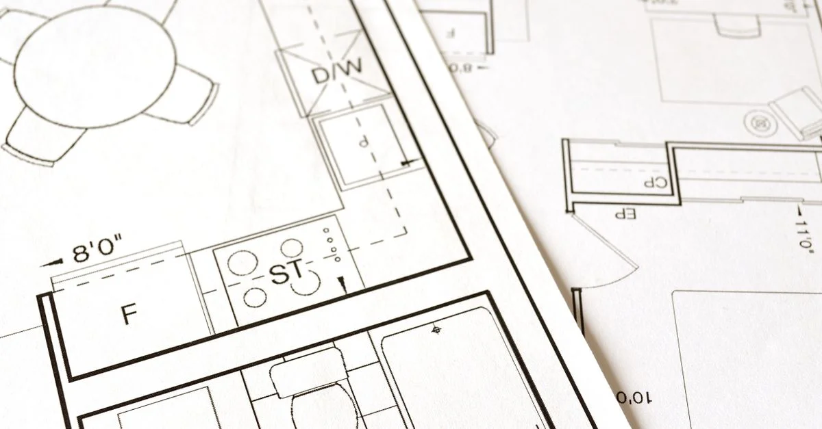Vue rapprochée d'un plan architectural sur papier montrant des agencements et des mesures de pièces détaillées.
