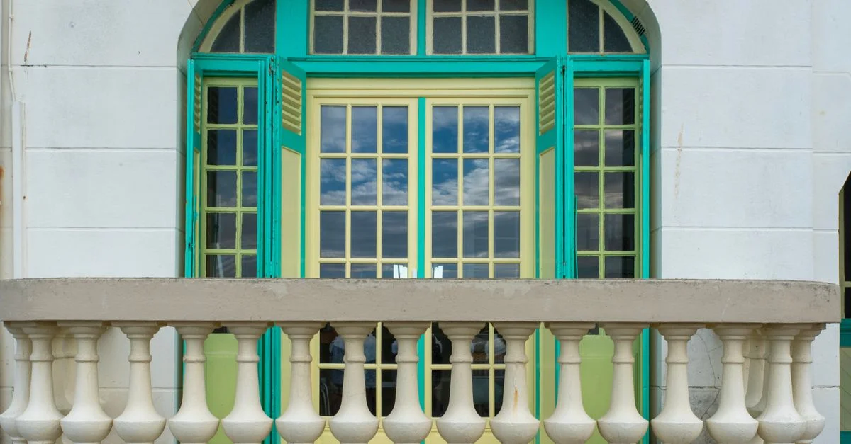 Balcon de style art déco vibrant avec des portes françaises colorées et une balustrade décorative.
