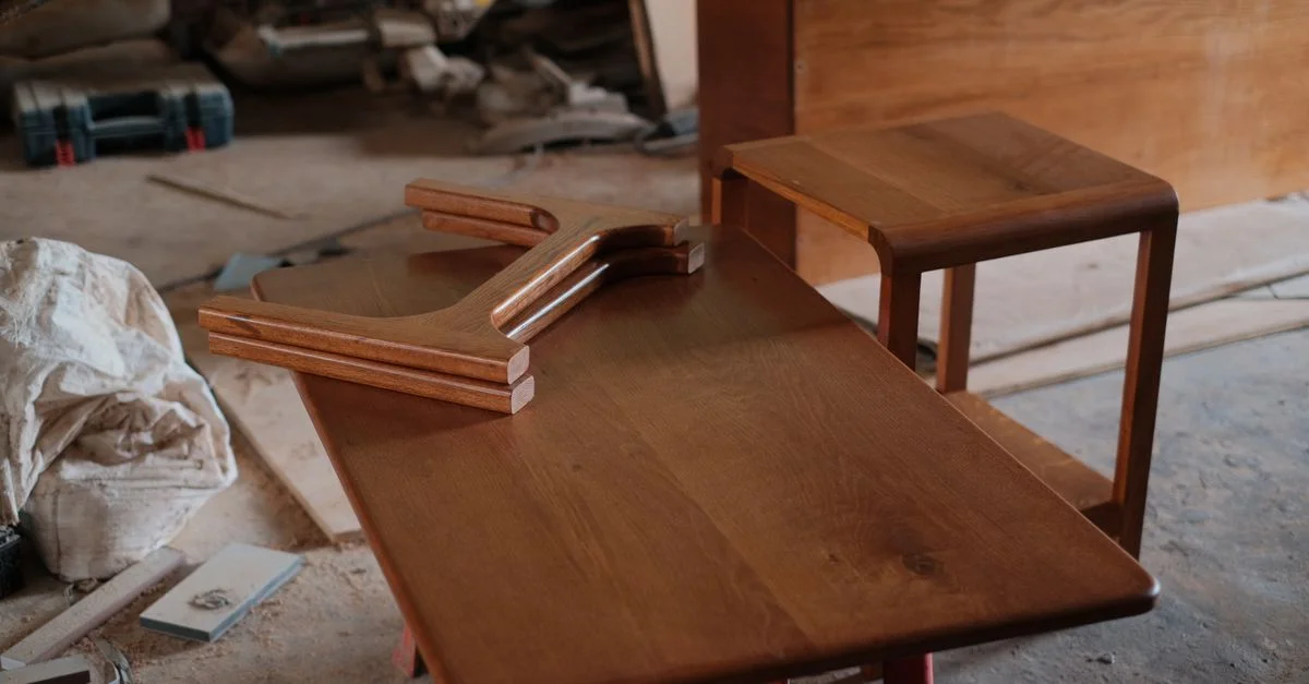 Des meubles en bois disposés sur une table d'atelier, témoignant d'un savoir-faire artisanal.