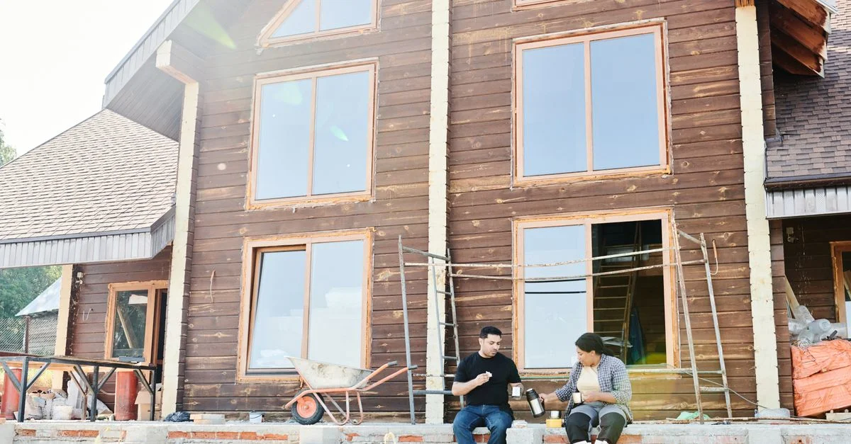 Deux personnes dégustant un café pendant une pause sur un chantier de construction de maison en bois.