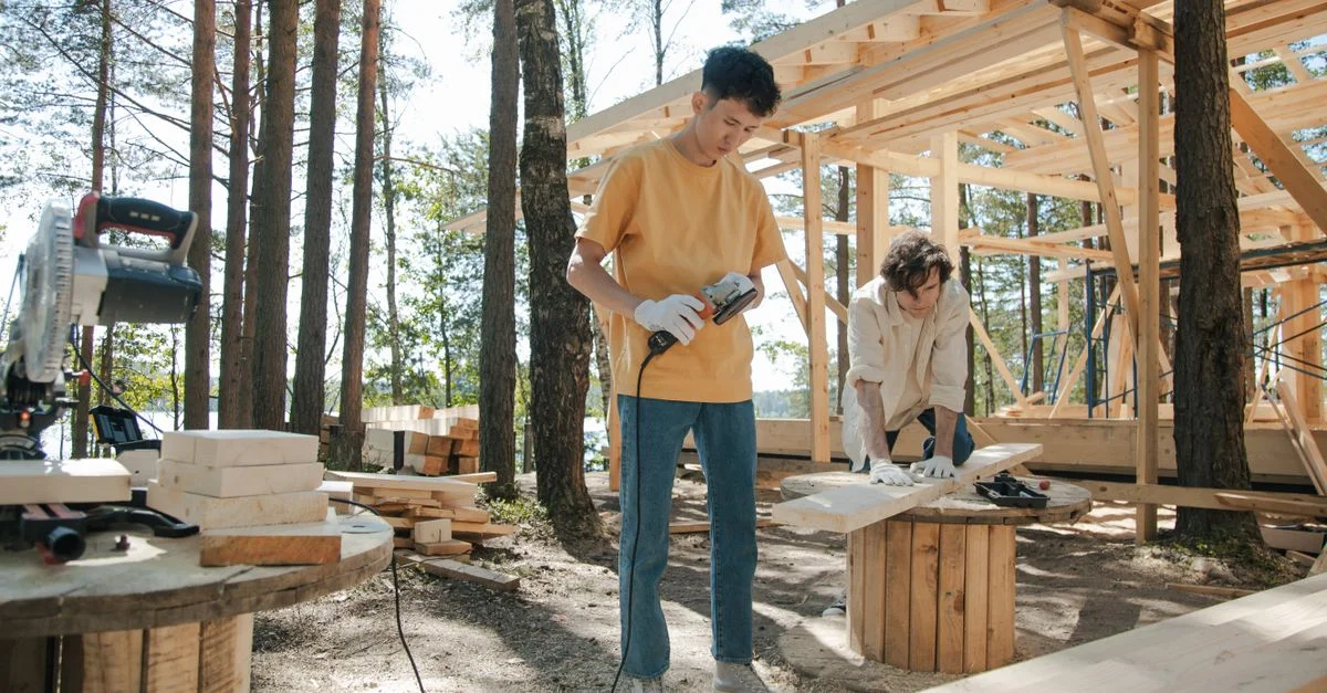 Deux jeunes hommes travaillant sur un projet de construction en bois dans une forêt.