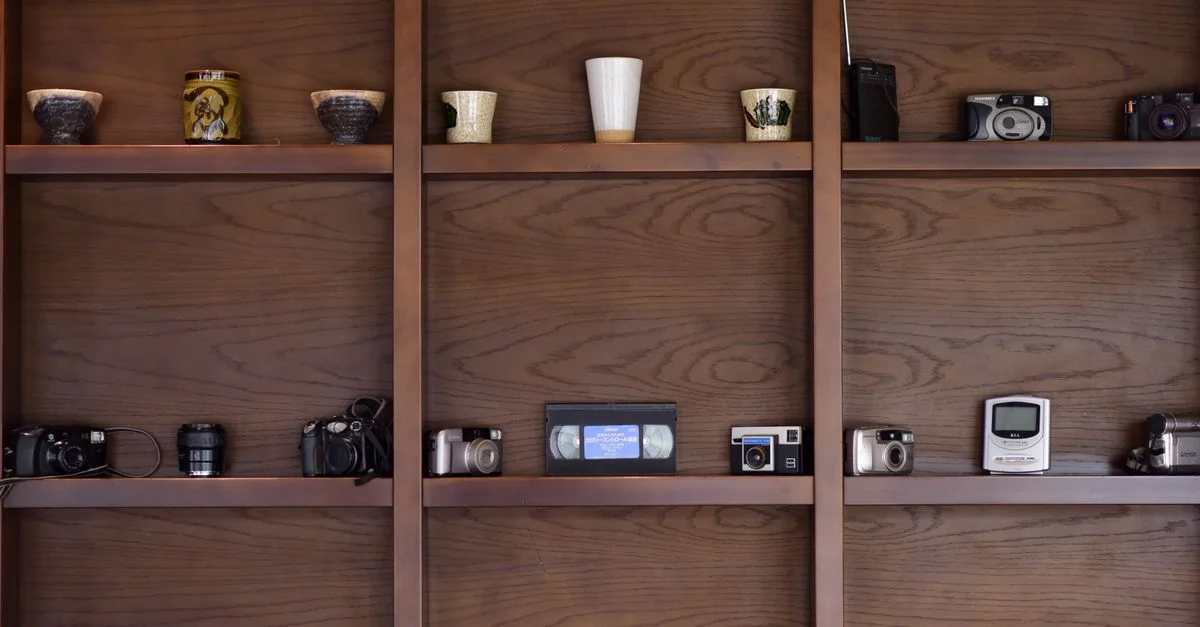 Une collection d'appareils photo vintage et d'objets décoratifs soigneusement disposés sur des étagères en bois.