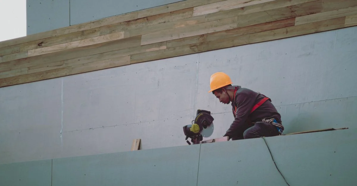 Ouvrier du bâtiment portant un casque de chantier utilisant une scie circulaire sur un chantier.