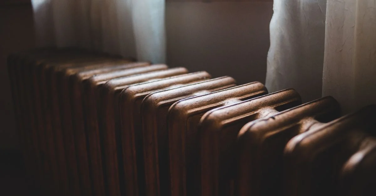 Radiateur vintage en fonte chaleureux avec lumière naturelle provenant de la fenêtre, créant une atmosphère intérieure confortable.