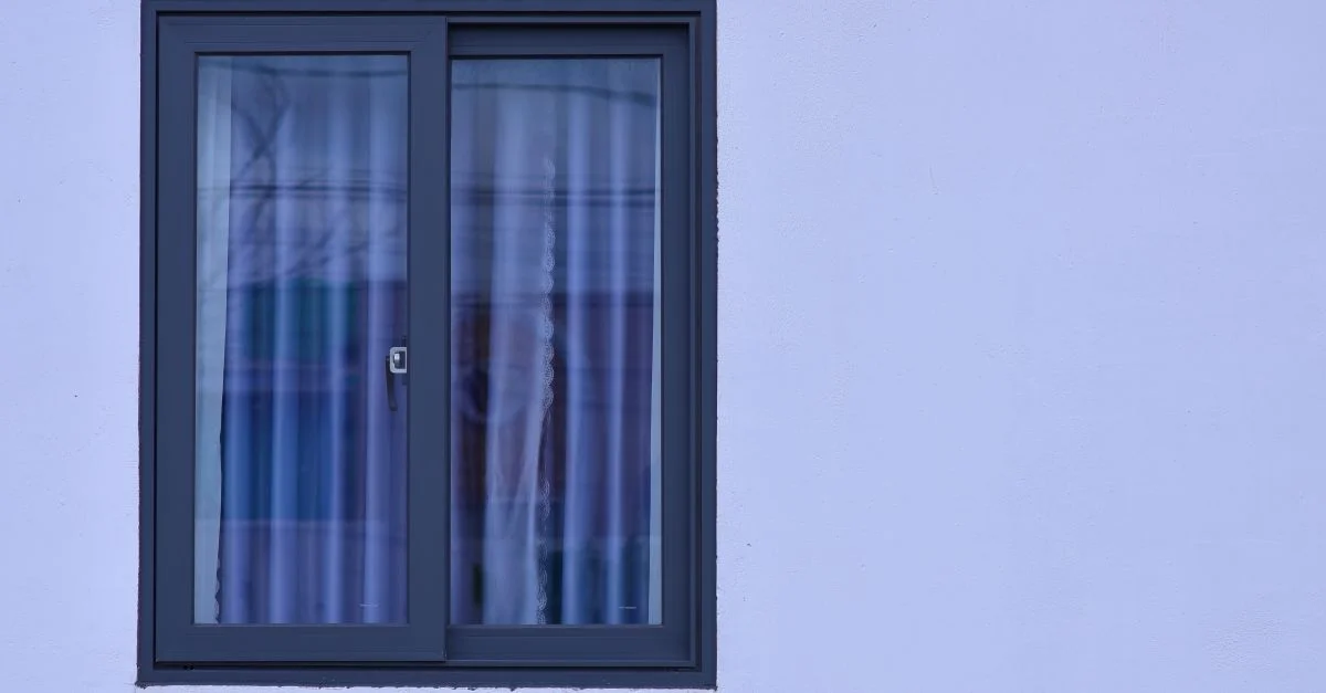 Une vue minimaliste d'une fenêtre moderne avec du verre dépoli sur un mur bleu clair.
