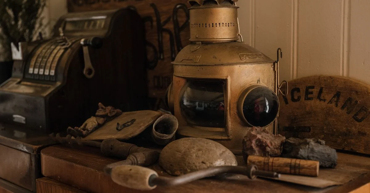 Une collection d'objets vintage comprenant une caisse enregistreuse et une lanterne sur un cabinet en bois.