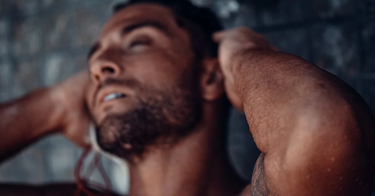 Gros plan sur un homme musclé et tatoué profitant d'une douche rafraîchissante.