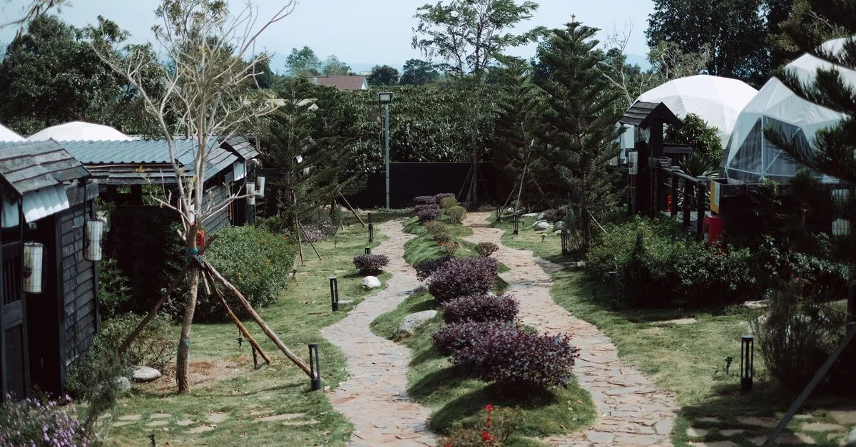Charmant chemin de jardin rustique avec une verdure luxuriante et des structures en forme de dôme, parfait pour les retraites.